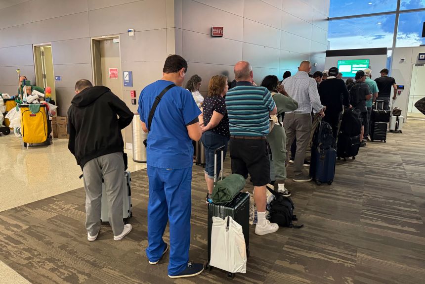Passengers seeks updates on their delayed flight at Louis Armstrong New Orleans International Airport, Wednesday, Aug. 6, in Kenner, Louisiana.