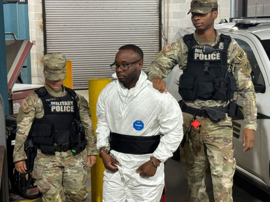 Sgt. Quornelius Radford, a suspect in the shooting of five soldiers at Fort Stewart, is escorted by military police into a booking room at the Liberty County Jail in Hinesville, Georgia, on Wednesday. (AP Photo/Lewis M. Levine)