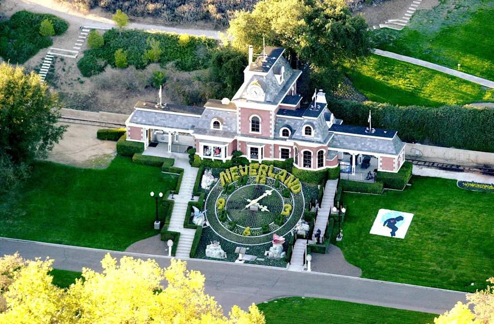 Aerial view of a large estate with a clock garden reading "Neverland" in front of a mansion, symbolizing a celebrity's famous residence