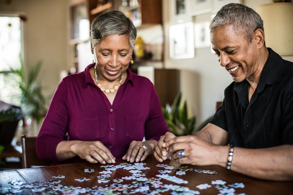 Senior couple (60yrs) assembling puzzle at home