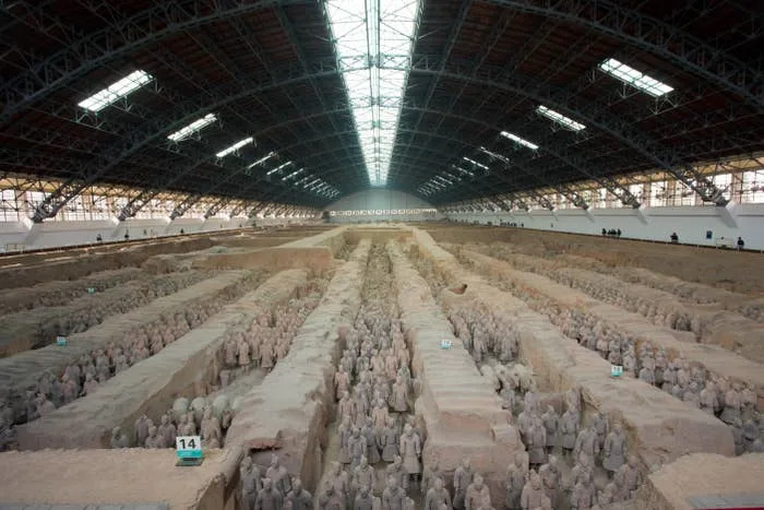 Terracotta Army statues displayed in large protective hangar at the excavation site, showcasing rows of ancient soldiers and horses