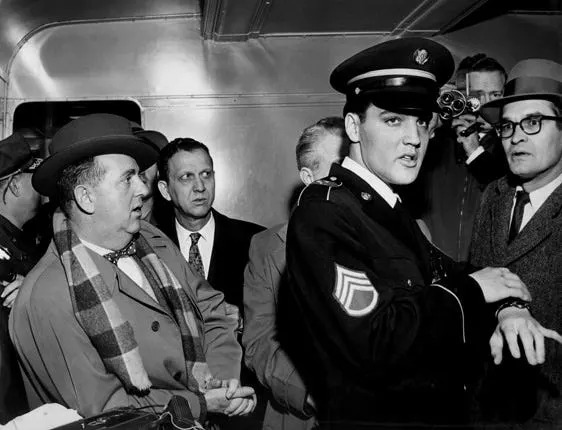 Col. Tom Parker, left, keeps a watchful eye on his client, Elvis Presley, as the singer returns to Memphis in 1960 after his stint in the Army.