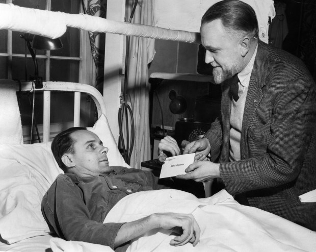 John Thompson, right, representing the Good Fellows organization, presents a cash gift to Stephen Grabowski, 36, at Hines Veterans Hospital on Dec. 19, 1953. Good Fellows was a charity that gave out gifts during the holidays. (George Quinn/Chicago Tribune) 