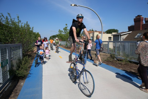 A very tall bike is among the procession of bikes...