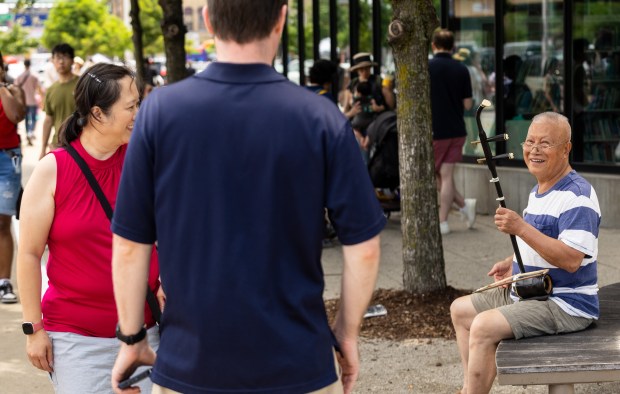Busker Zhen Jinling, right, thanks Eric and Jennifer Burpee of Midlothian after they gave him money outside the Chinatown Branch of the Chicago Public Library on July 27, 2025, in Chicago. (Dominic Di Palermo/Chicago Tribune)