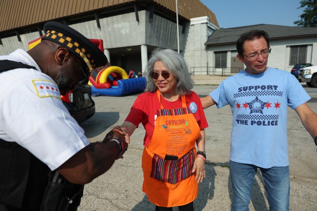 Maria Pike, a gun violence survivor advocate, is greeted by a police supervisor and Ald. Raymond Lopez, 15th, during a National Night Out event at Ogden Park in the Englewood neighborhood of Chicago on Aug. 5, 2025. (John J. Kim/Chicago Tribune)