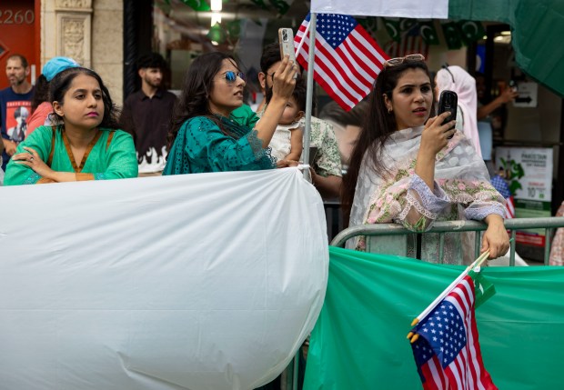 People watch from the sidewalk as participants march down West Devon Avenue to celebrate Pakistan Independence Day on Aug. 10, 2025, in the West Rogers Park neighborhood of Chicago. (Brian Cassella/Chicago Tribune)