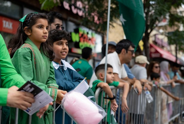 People watch from the sidewalk as participants march down West Devon Avenue to celebrate Pakistan Independence Day on Aug. 10, 2025, in the West Rogers Park neighborhood of Chicago. (Brian Cassella/Chicago Tribune)
