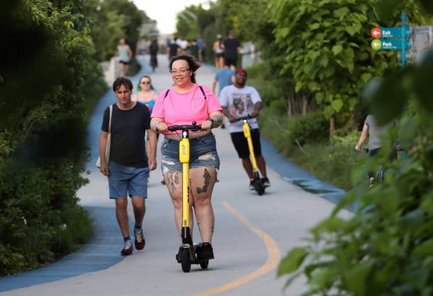 People ride electric scooters along The 606 on June 25,...