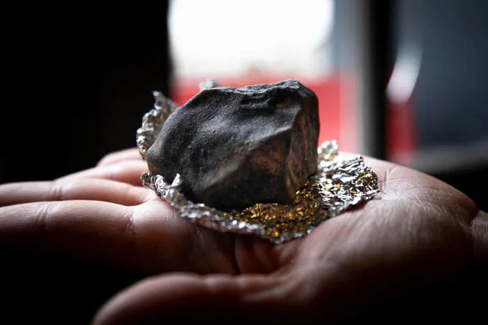 A hand holds a rock wrapped in crumpled foil