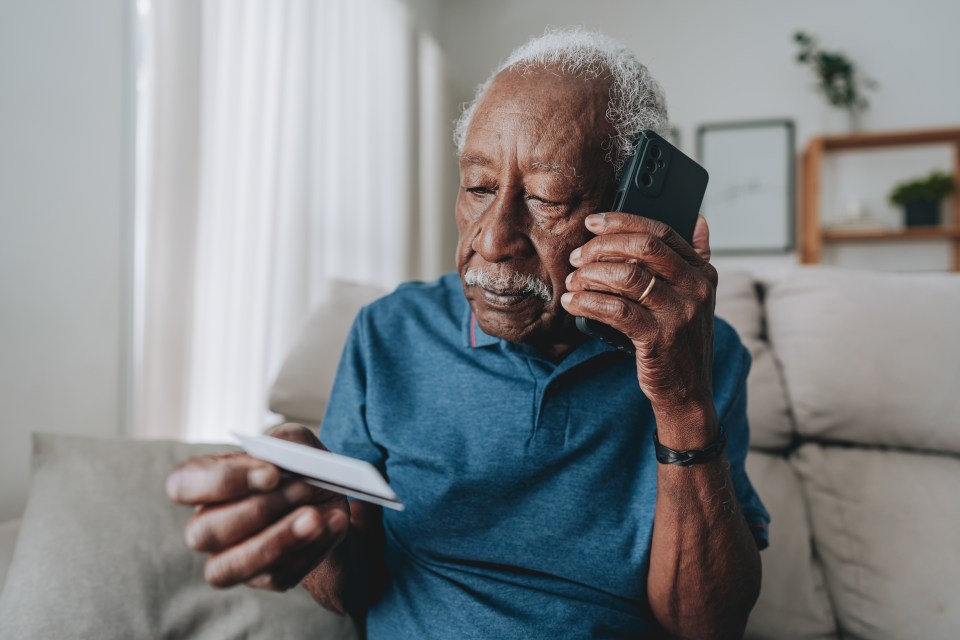 Elderly man using smartphone and credit card.