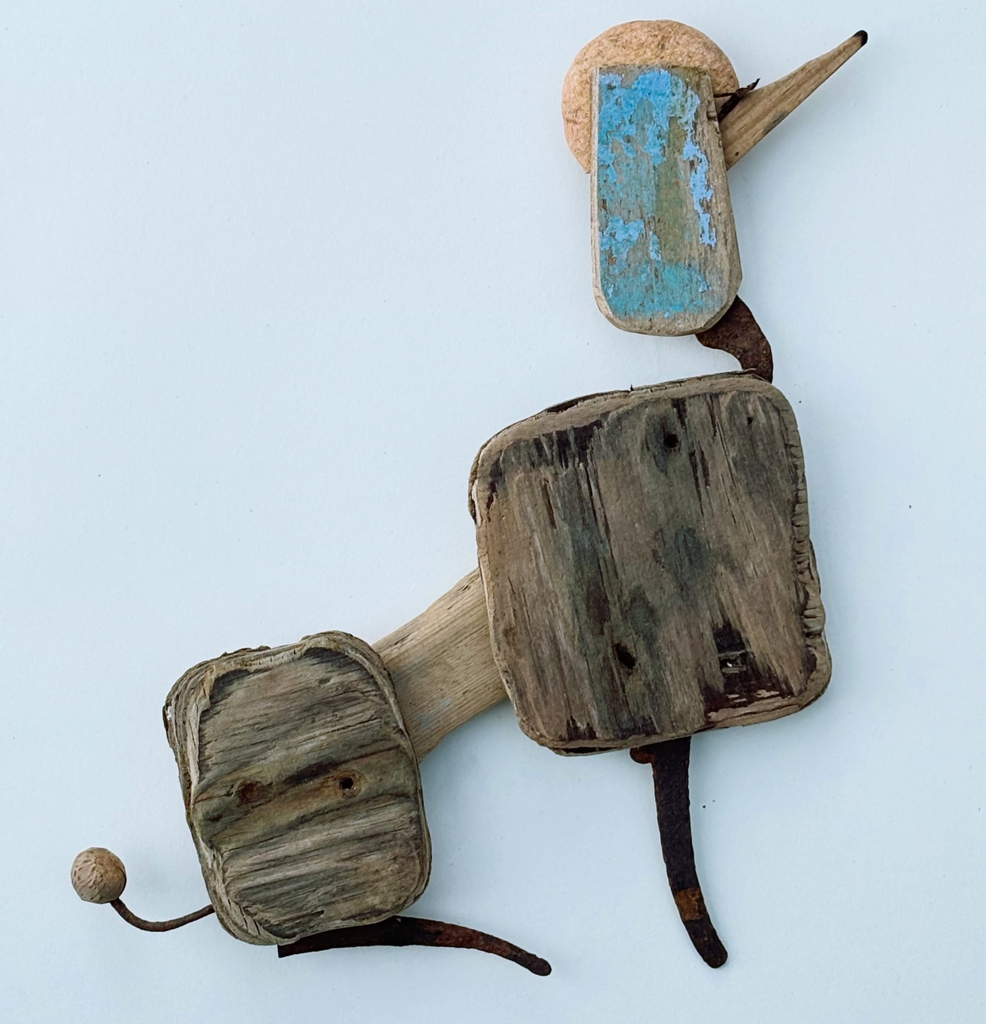 a poodle sculpture made of worn blue and brown wood