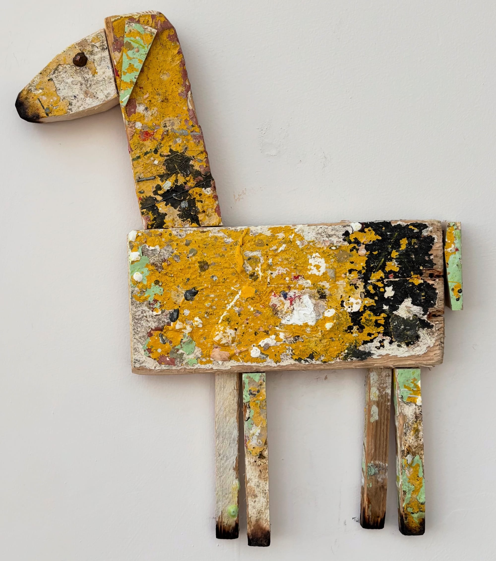 a sheep sculpture made of worn yellow wood splattered with paint