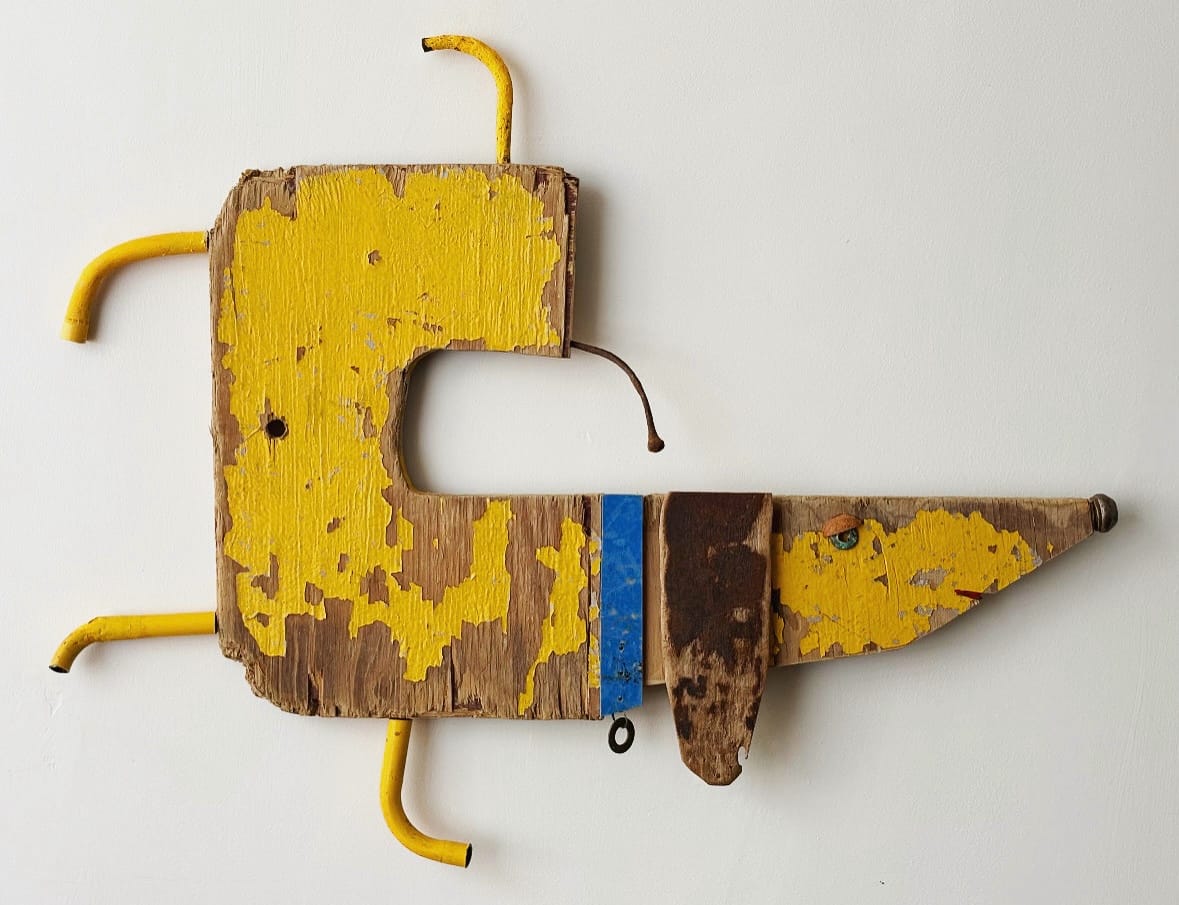 a dog sculpture made of worn yellow wood