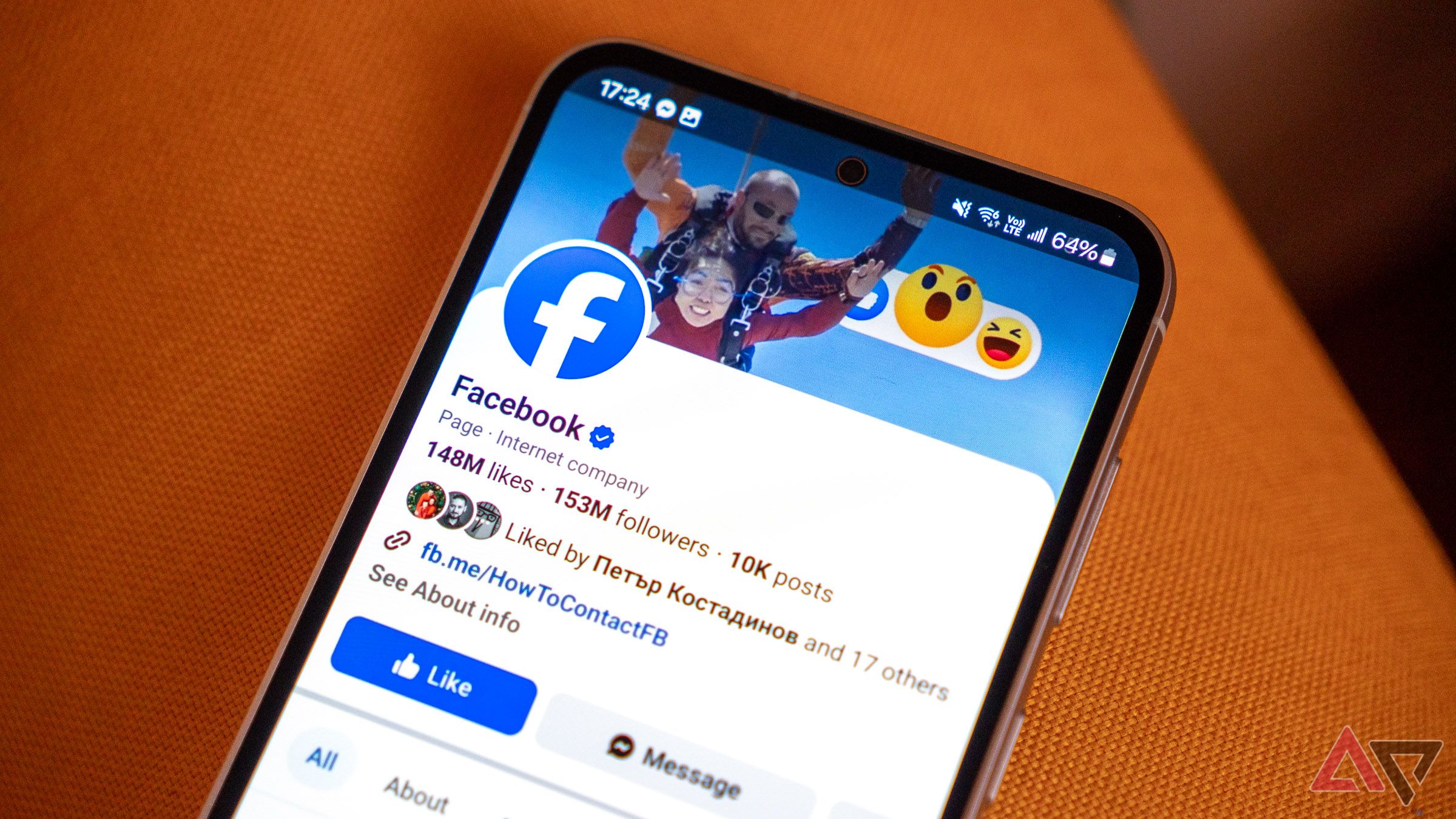 the facebook page of facebook shown on a samsung phone on the armrest of a couch