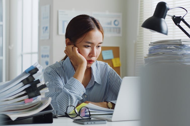 Woman at laptop surrounded by papers