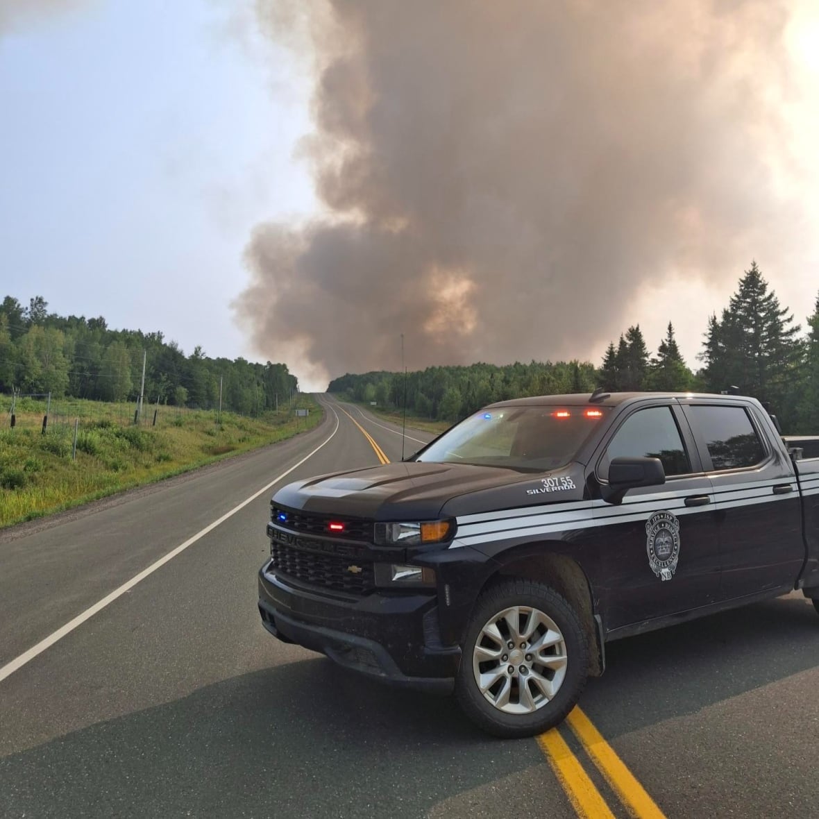 A black truck parked blocking a highway.