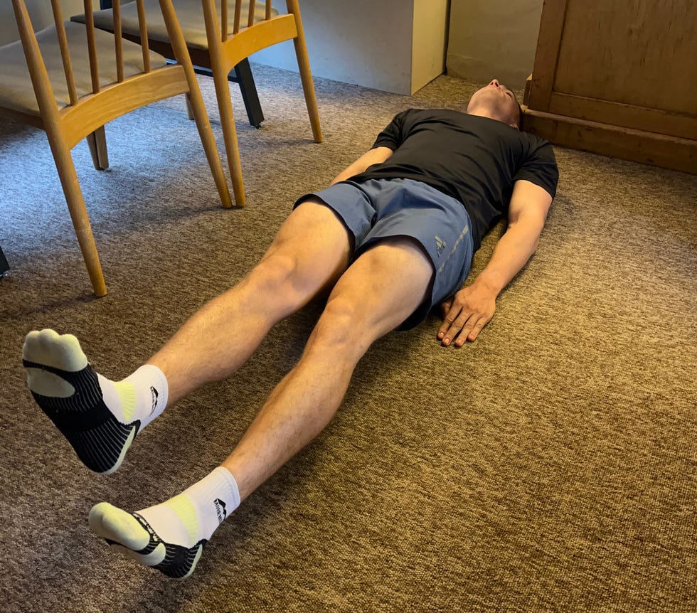 an individual lying flat on the floor in a relaxed position