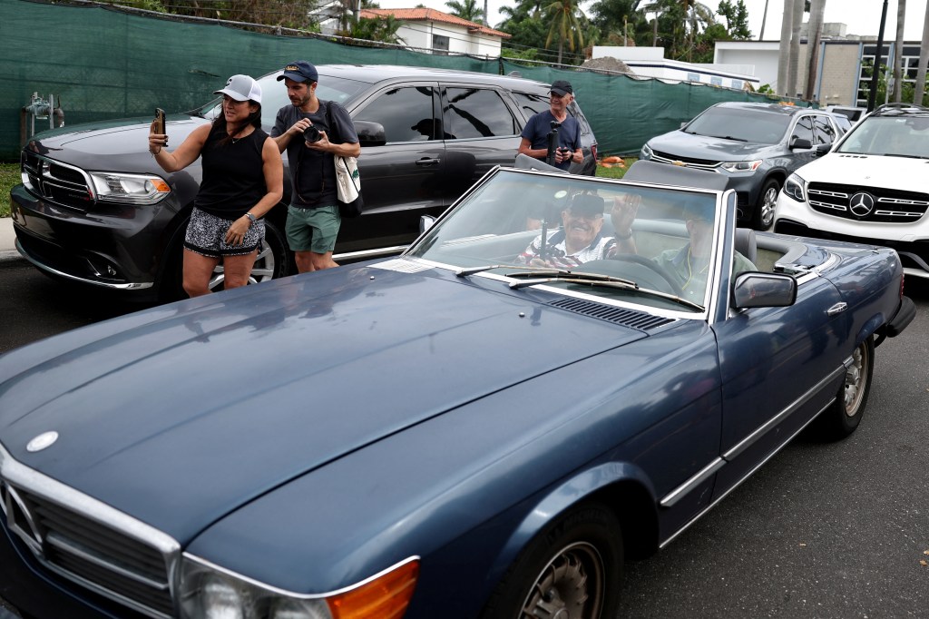 Rudy Giuliani in a convertible, waving to onlookers.