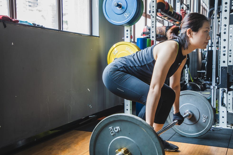 asian woman lifting weights in a gym
