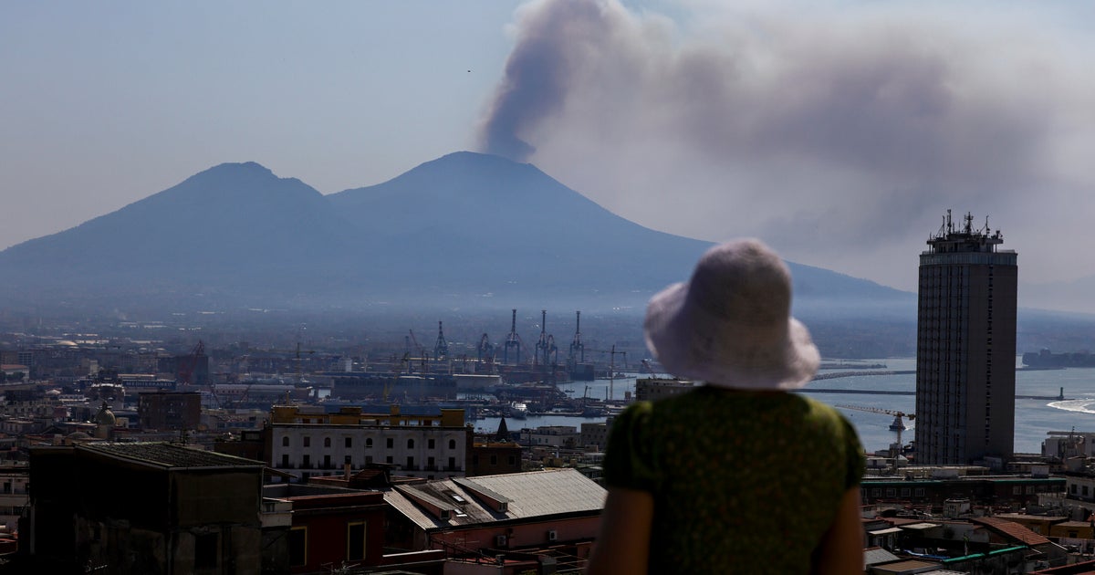 A touritst looks at the smoke of a big fire on Vesuvius