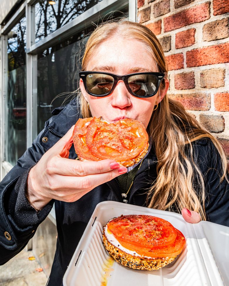A visitor from Philadelphia wastes no time trying her order from Apollo Bagels in Manhattan's West Village.