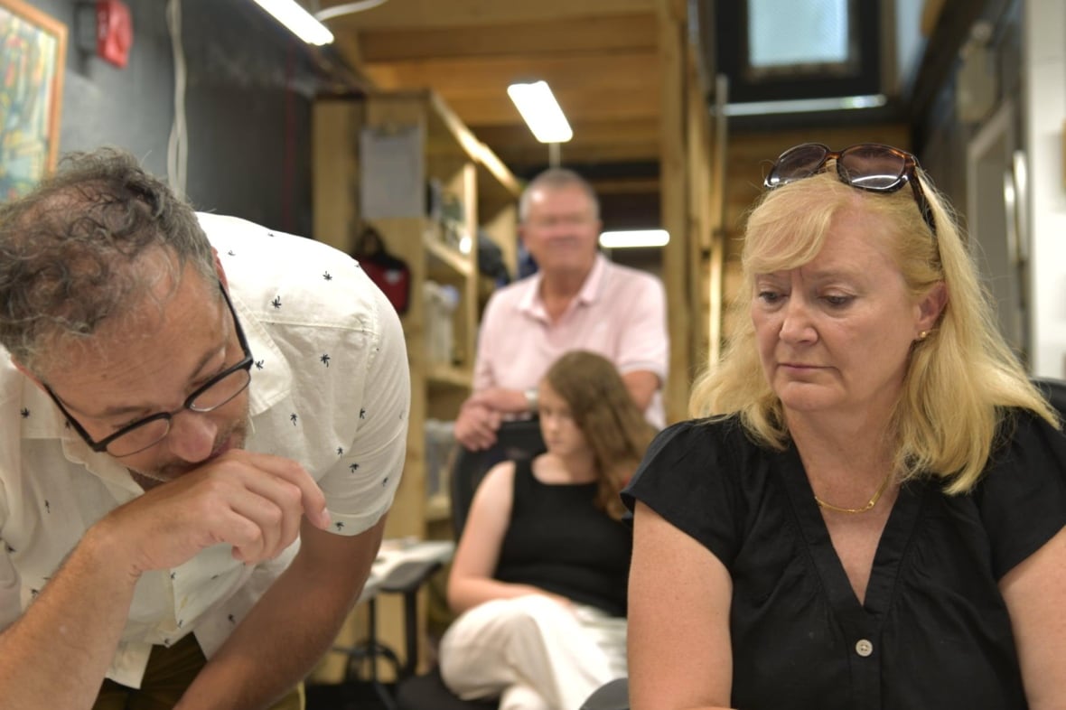 A man and a woman look down at a table 