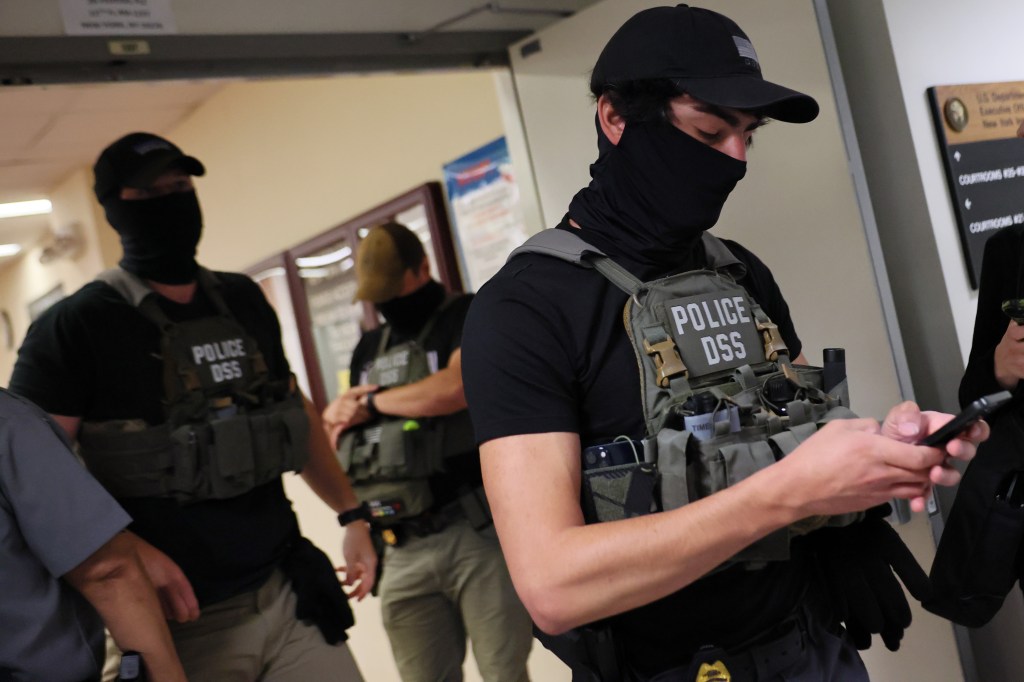 Police officers in tactical gear inside a courthouse.