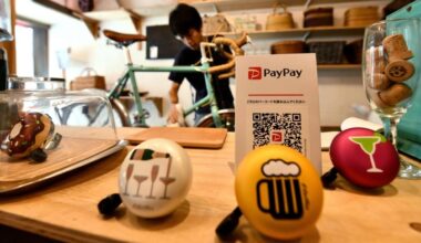 A man works on a bicycle in his Tokyo shop, with a PayPay QR code sign displayed on the counter