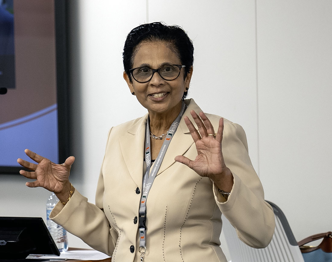 Dr. Latha Chandran speaking by a podium
