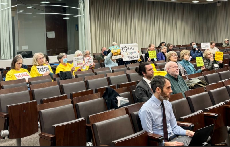 Community members hold signs urging the county to replace the current trash incinerator at a County Council work session on Jan. 28, 2025.