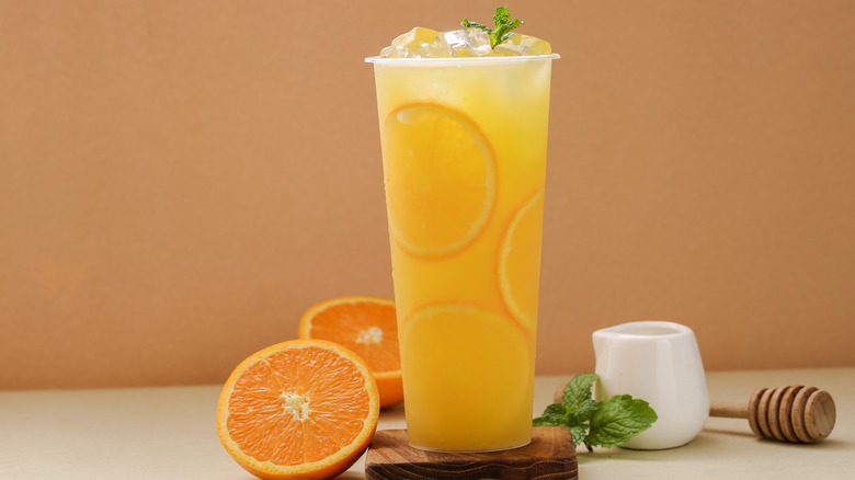 A yellow-orange drink with sliced oranges beside it