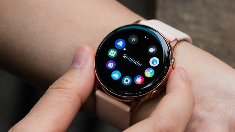 A person wearing a Samsung Galaxy Watch and using its physical controls.