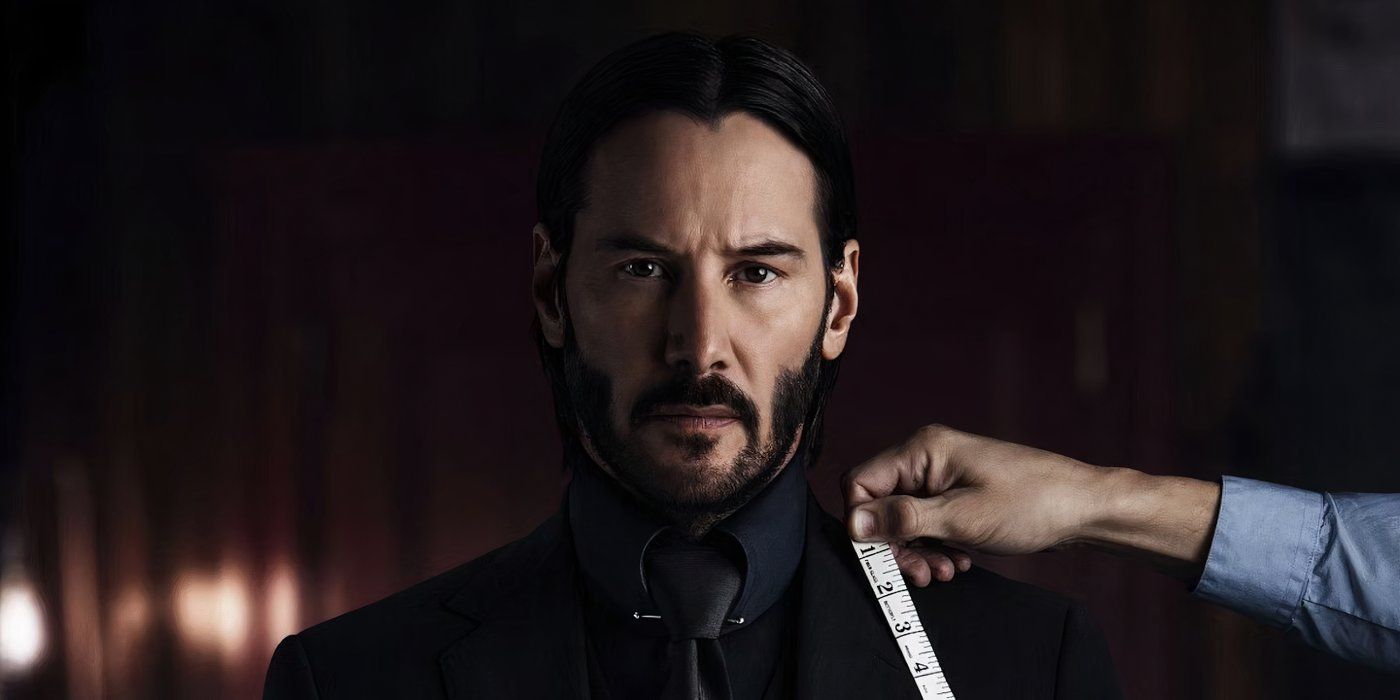 John Wick stares into camera as a tailor inspects his black suit in the movie John Wick: Chapter 2.