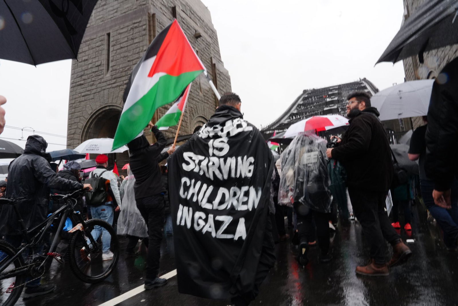 A protester wears a cape that reads: "ISRAEL IS STARVING CHILDREN IN GAZA"