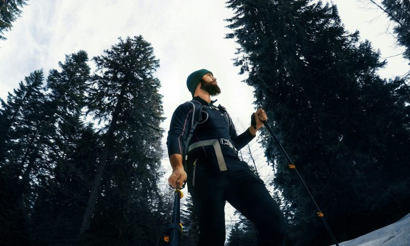 Man walking with Nordic walking poles outside by the trees wearing a hat