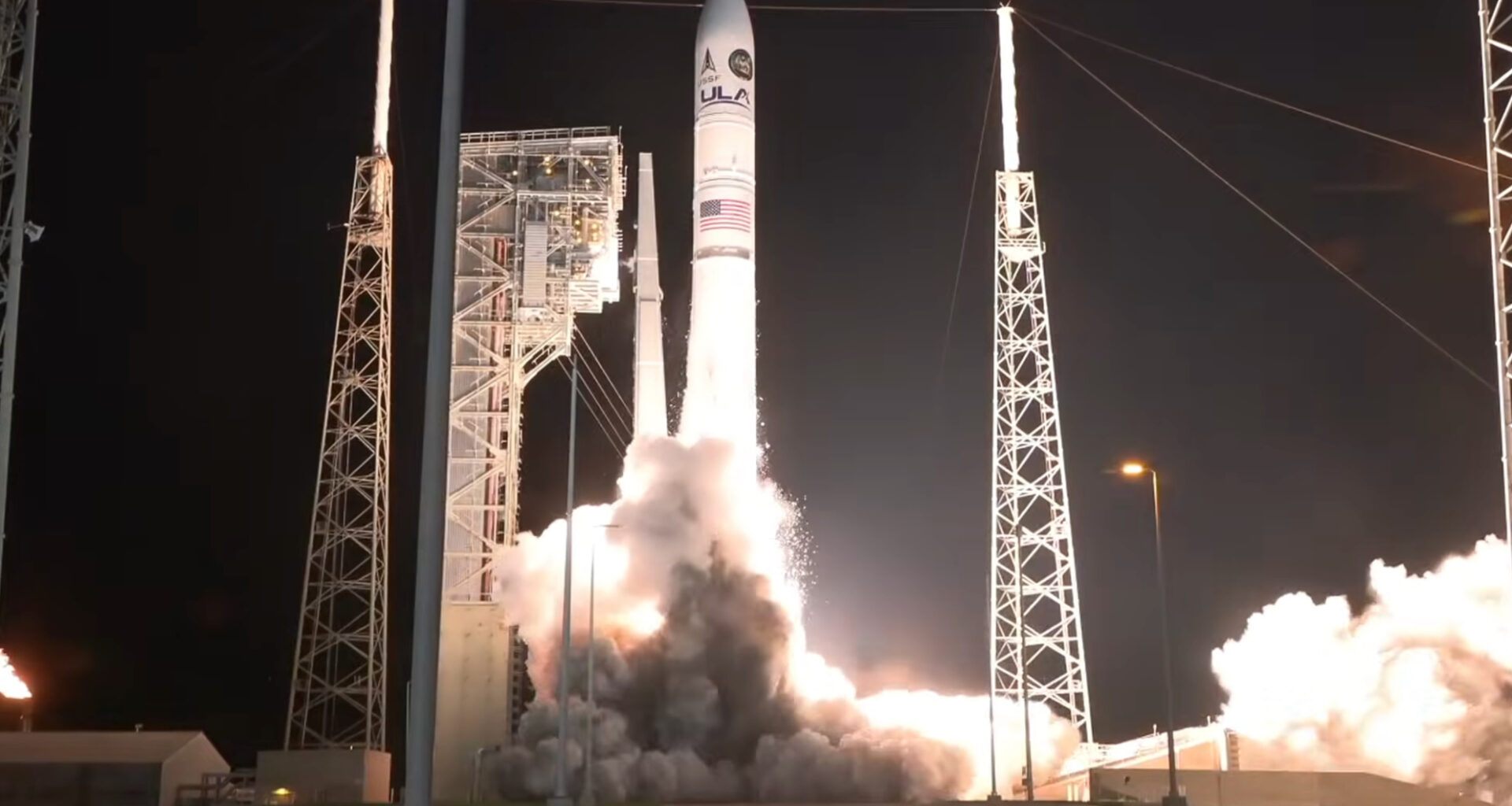 a large white rocket launches into a dark night sky