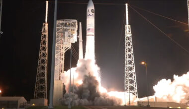a large white rocket launches into a dark night sky
