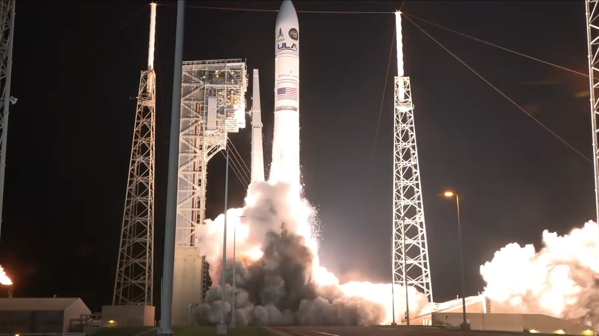 a large white rocket launches into a dark night sky