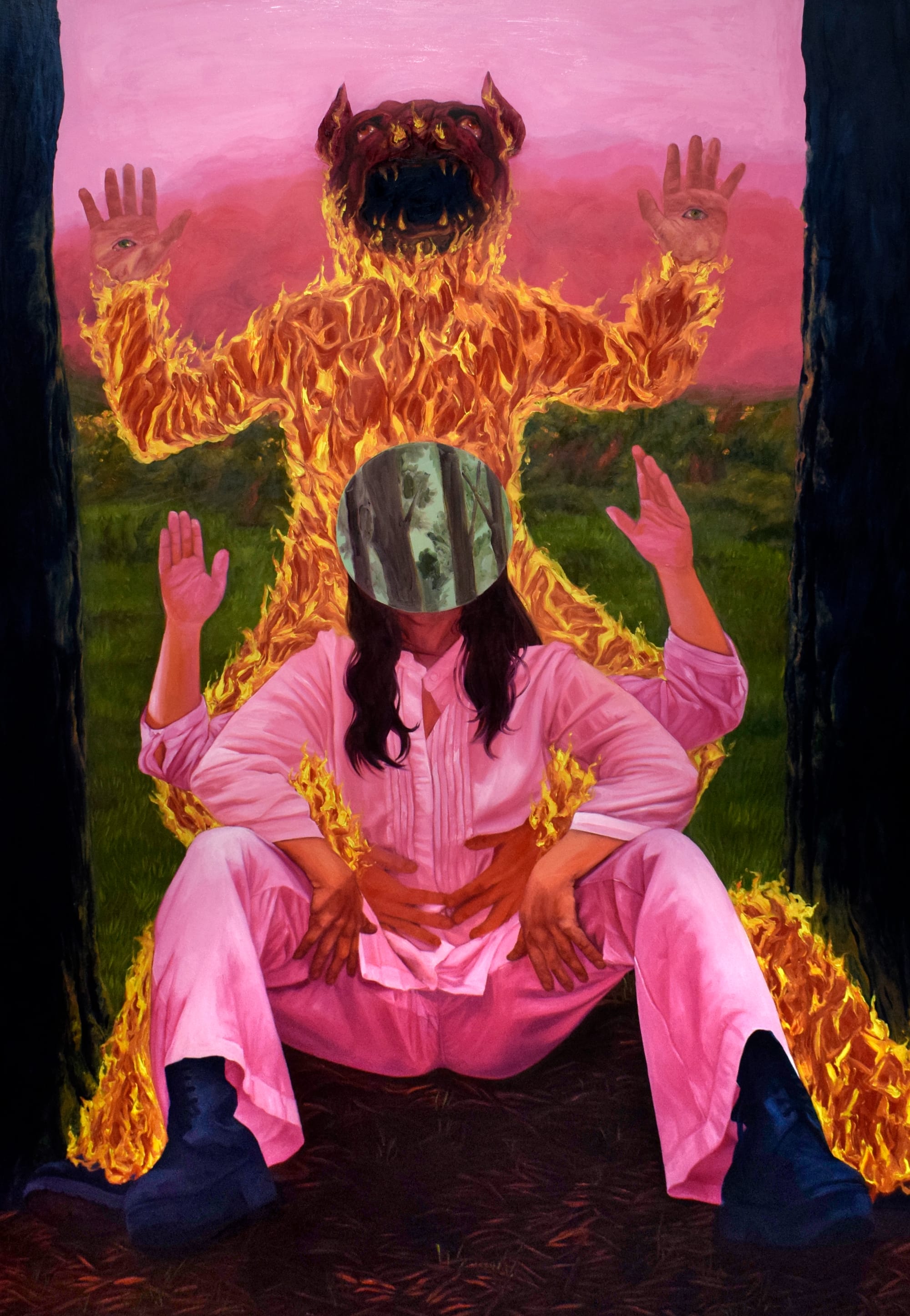 a figure in a pink jumpsuit and green mask sits on the ground with her arms raised and a figure on fire directly behind her