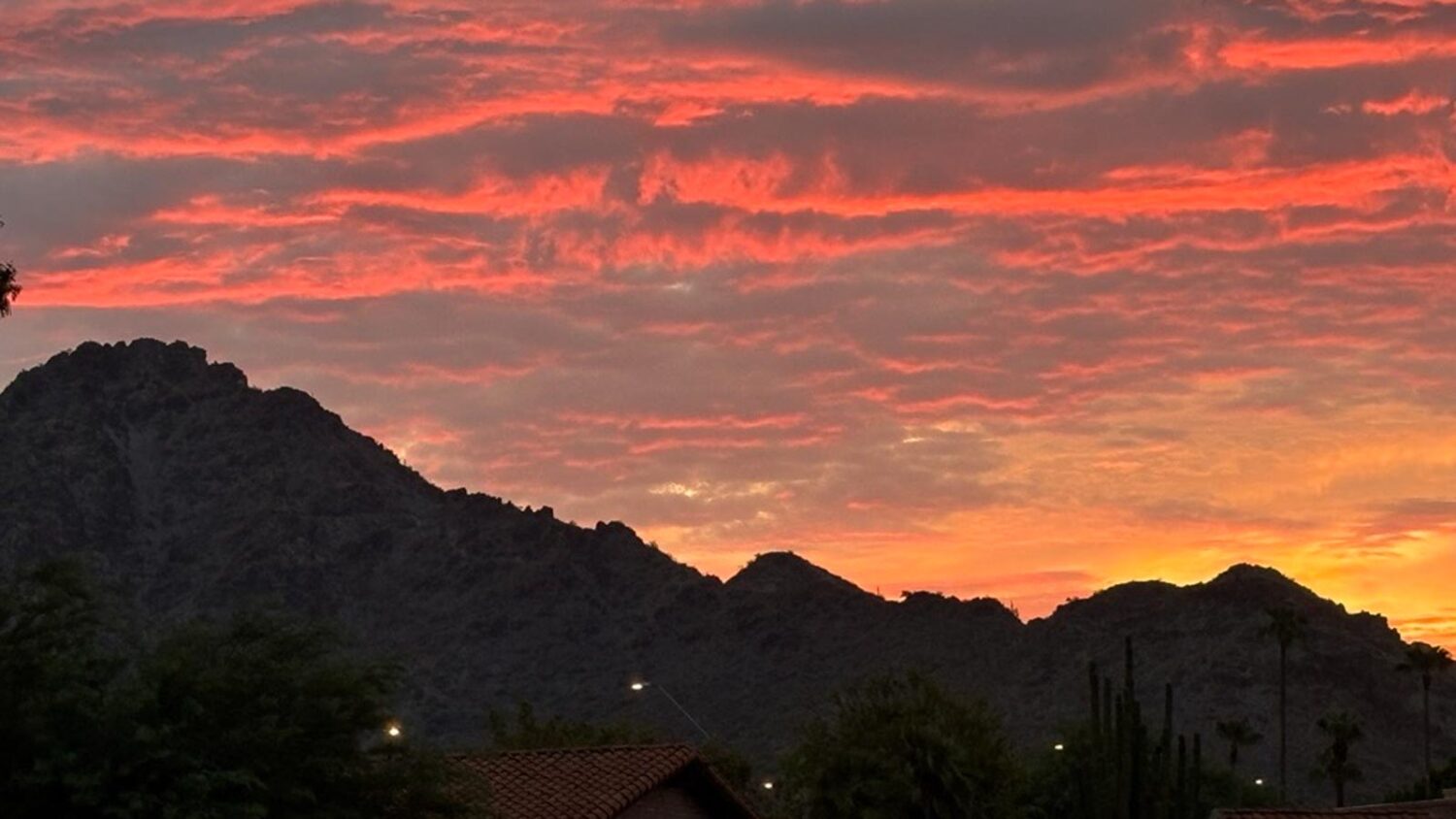 Clouds glow as the sun rises over the Piestewa Peak area in Phoenix after a night of monsoon storm ...
