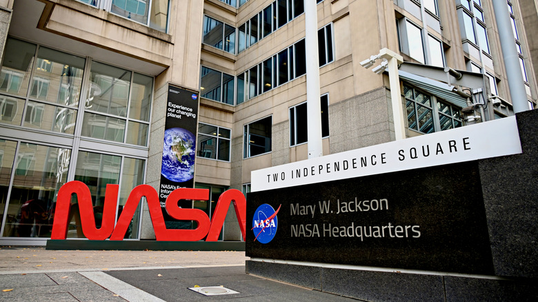 A large, bright red "NASA" logo in front of the Mary W. Jackson NASA Headquarters building stands out on an overcast day in the Nation's capital.