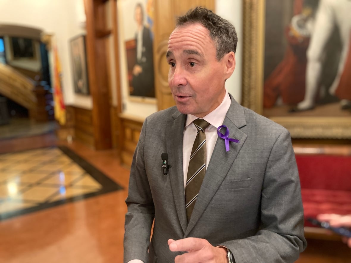 A man in a suit is speaking to reporters inside the legislature building.
