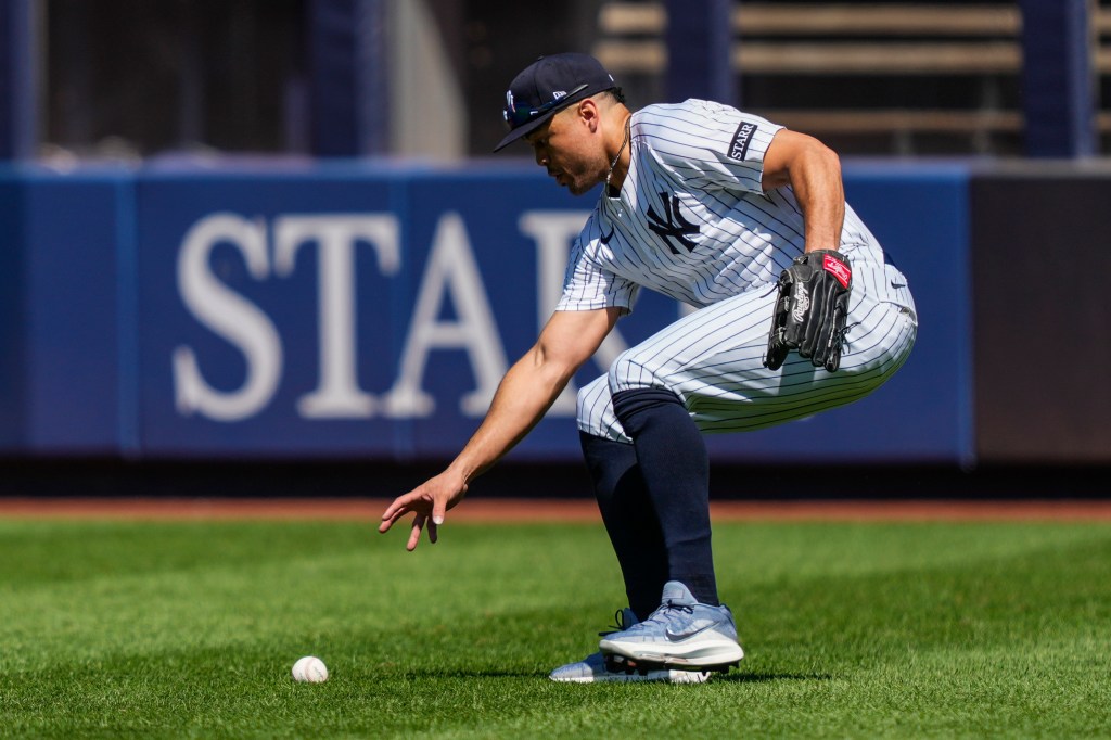 Giancarlo Stanton of the New York Yankees reaching for a baseball.