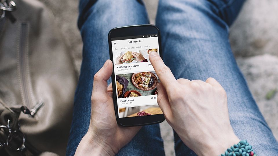 A person pressing on the Uber Eats app while sitting