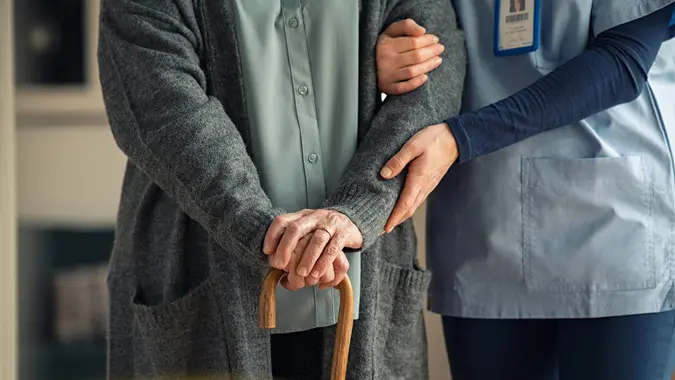 Nurse assisting senior with walking cane stock photo