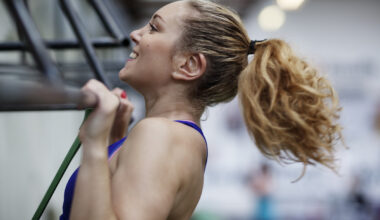 Smiling woman performing a pull-up in a gym, with her chin above the bar