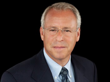 Herman in a black suit jacket light shirt and tie in a formal business photo