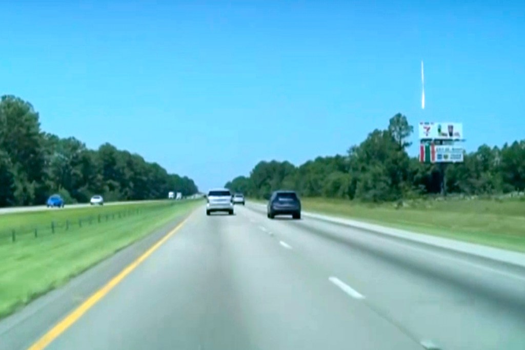 Bright object in sky over highway.