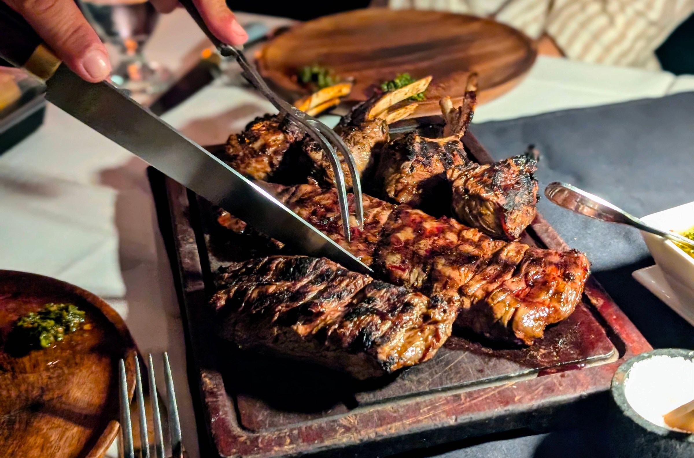 Knife cutting into steak at Carlitos Gardel on a wood cutting board